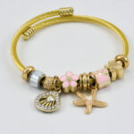 Gouden armband met roze kralen en elegante bedels