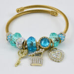 Gouden armband met turquoise accenten en gedetailleerde bedels