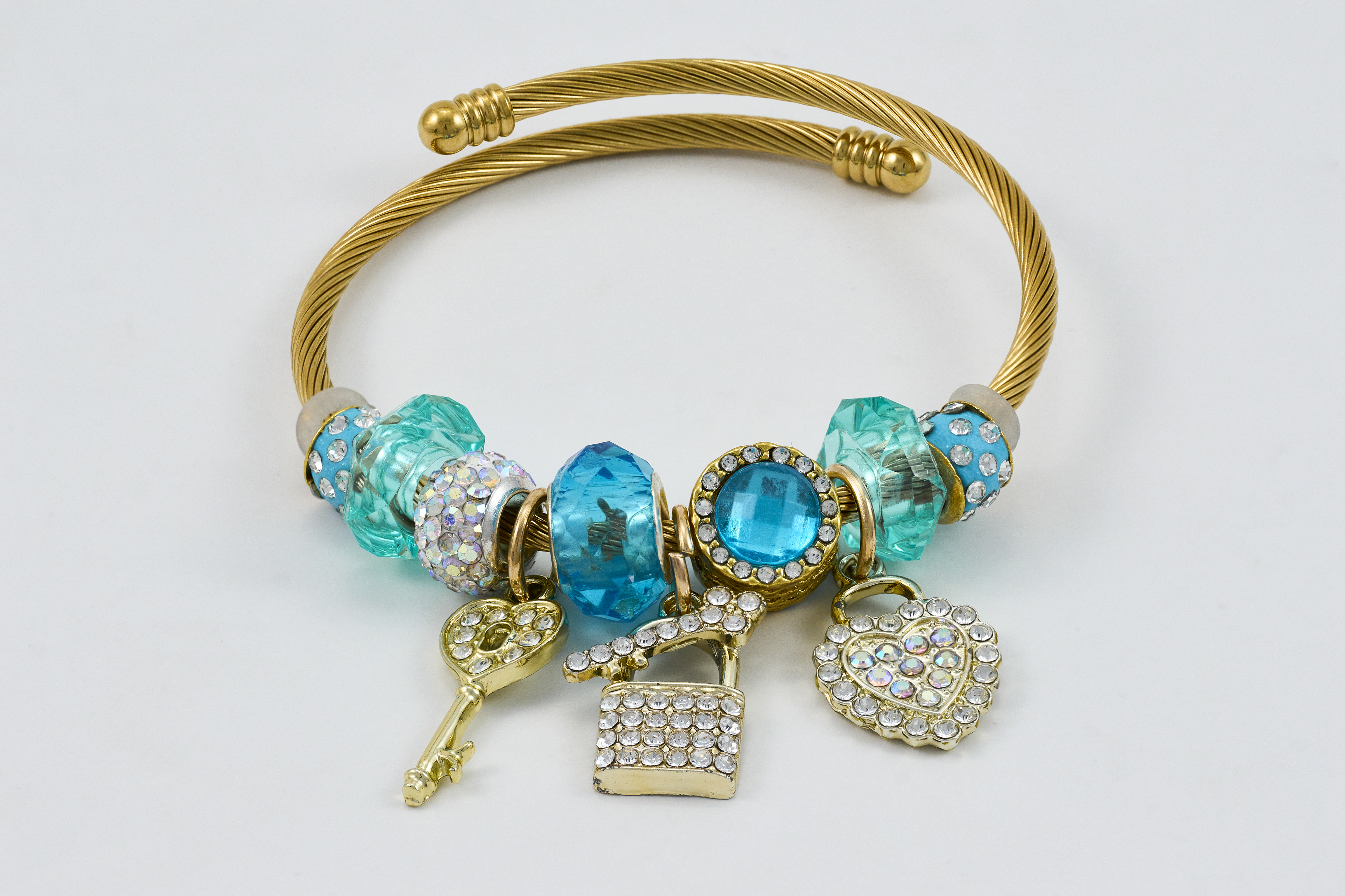 Gouden armband met turquoise accenten en gedetailleerde bedels